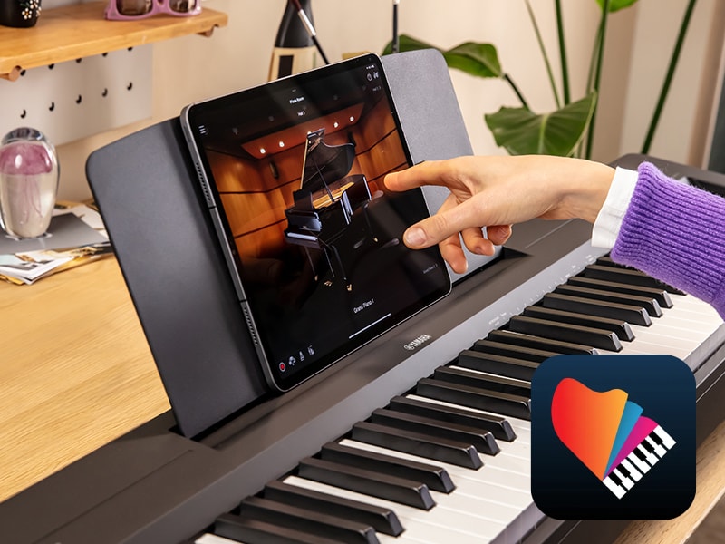 The Yamaha “Smart Pianist” app icon, together with a tablet placed on the music stand of the P-143BT