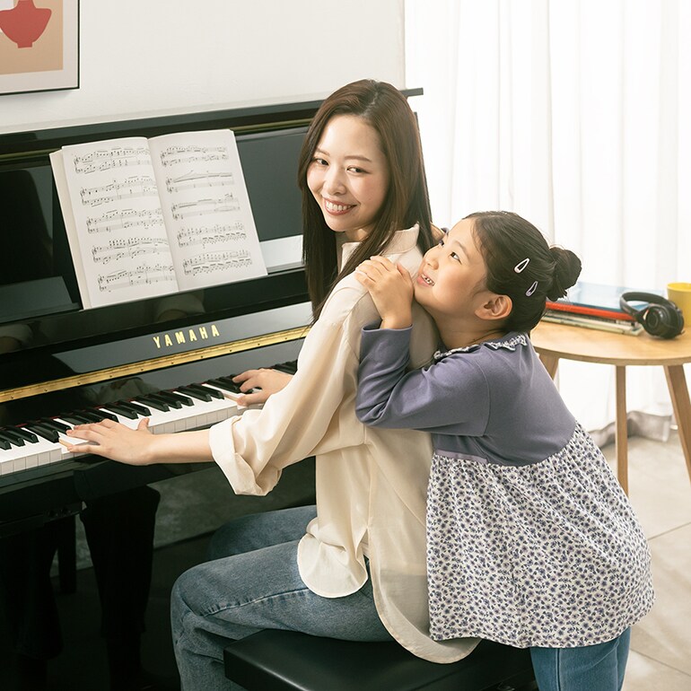 A mother and daugter enjoy playing the upright piano B series